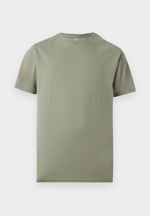 T-shirt με κοντά μανίκια και στρογγυλή λαιμόκοψη σε απαλό ελαιδένιο πράσινο χωρίς σχέδια, απλωμένο επίπεδα πάνω σε απλό ανοιχτό φόντο.