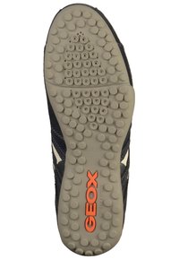 Black sneaker with a textured mesh upper and a rubber sole. Features circular traction dots and "GEOX" logo in orange on the sole.