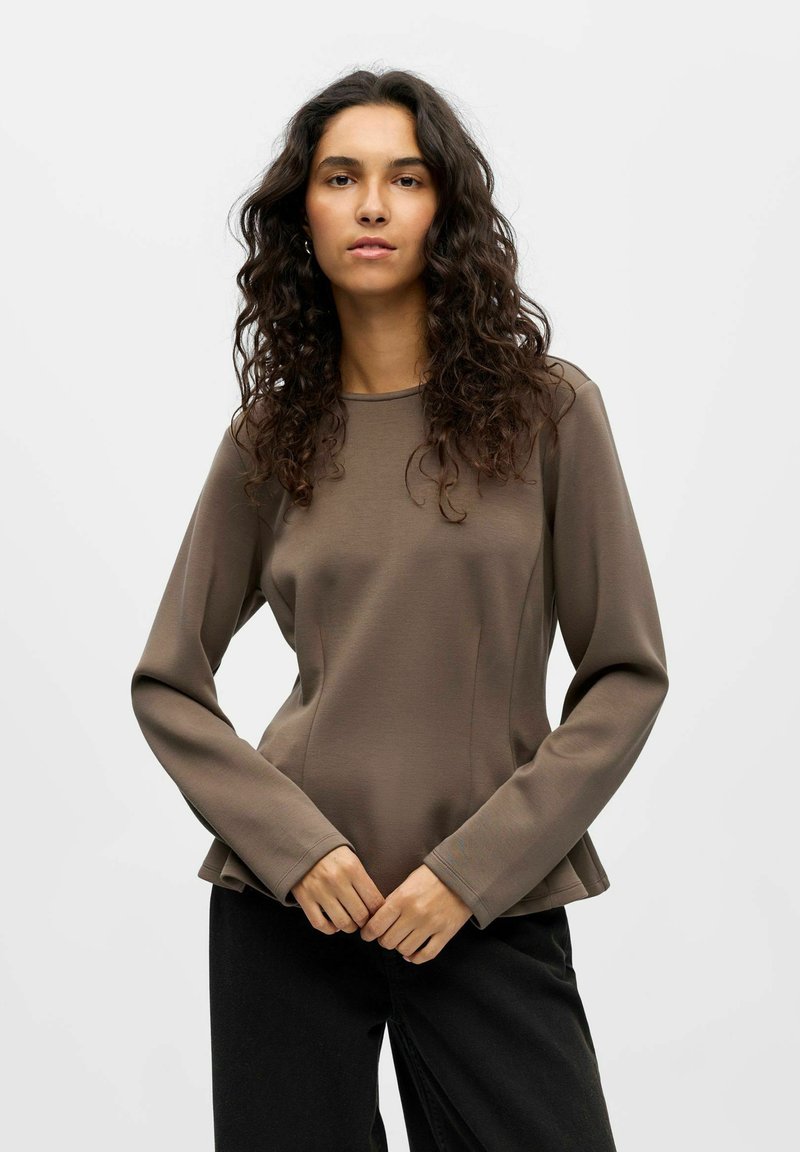 Rjava dolgosleeve majica s krožnim ovratnikom in rahlo razširjenim robom, izdelana iz gladkega blaga. Model jo nosi s črnimi hlačami.