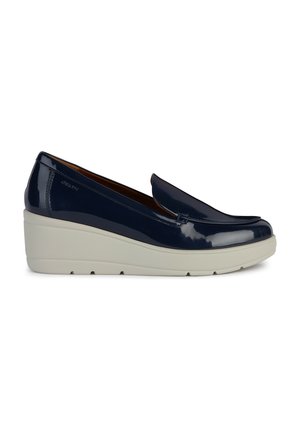 Mocassin compensé en cuir verni marine avec une finition lisse, présentant une ligne supérieure subtile et une semelle en caoutchouc blanche.