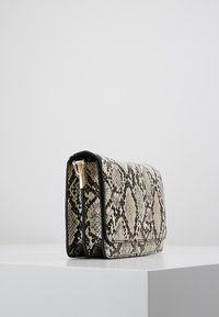Borsa con motivo di pelle di serpente, dal design strutturato, caratterizzata da una chiusura dorata e rifiniture in pelle nera. Esterno testurizzato con pattina pieghevole.