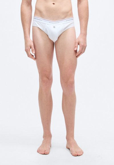 Culottes en coton blanc avec une ceinture étroite ornée de textes gris et rose. La coupe est ajustée, avec un design simple et minimaliste.
