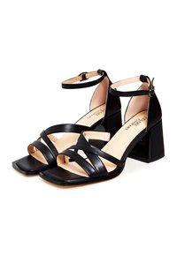 Zwarte hakken sandalen met een vierkante neus en meerdere gekruiste banden. Enkelband met verstelbare gesp. Gladde, glanzende leren afwerking en blokhak.