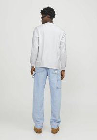 Long-sleeve white cotton shirt paired with light blue denim cargo pants featuring side pockets, made from soft, lightweight fabric.