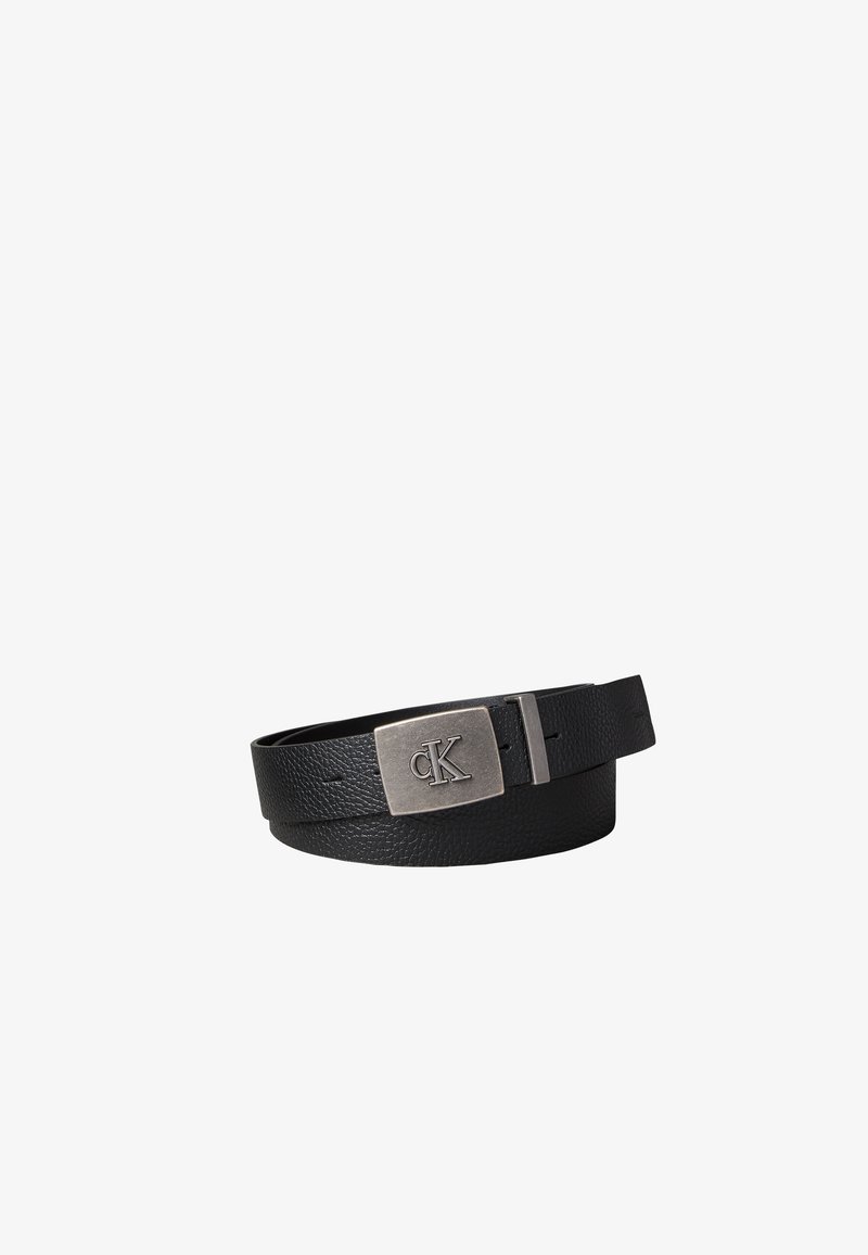 Ceinture en cuir noir texturé avec boucle rectangulaire en argent gravée du logo "cK", enroulée sur un fond blanc.