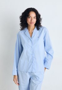 Blå och vitrandig pyjamasuppsättning som innehåller en skjorta med knappar och långa ärmar samt matchande byxor. Tillverkad av mjukt, lätt tyg.