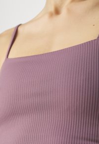 Mauve rebrasti top s tankom s tankim trakama, s kvadratnim izrezom i teksturiranim materijalom koji stvara suptilan vertikalni uzorak.