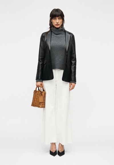 Blazer en cuir noir, pull à col roulé gris, jean blanc à jambes larges avec ourlet effiloché, sac à main texturé marron et escarpins noirs pointus.