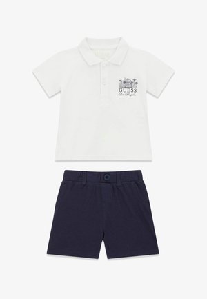Polo blanc à manches courtes avec l'inscription "Guess Los Angeles" et un graphisme, associé à un short bleu marine à boutons pour enfants.