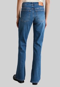 Blauwe denim flared jeans met een medium taille, afgewerkt met een tan leren label op de taille en vier klassieke zakken.