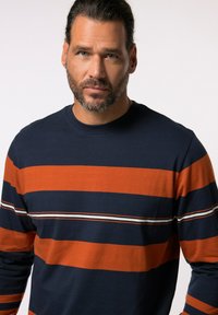 Camisa de manga larga de la marina con rayas horizontales naranjas y blancas. Cuello redondo y material de algodón suave. Corte relajado sin logotipos visibles.