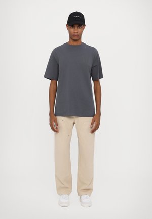 Gray short-sleeve t-shirt, beige loose-fit pants, and white sneakers. Black cap with embroidered text. Simple and minimalistic design.