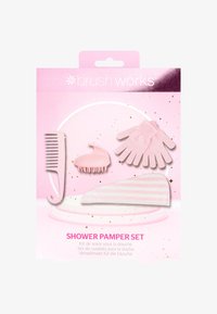 Rosa duschset för avkoppling med en bredtandad kam, hårbottenmassager, exfolierande handskar och randig hårband på glittrande bakgrund.
