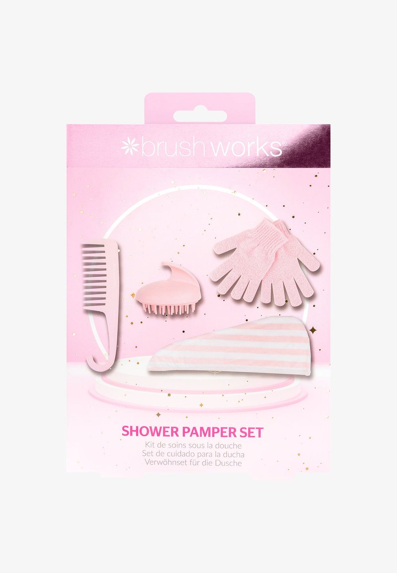 Ensemble de soins en rose comprenant un peigne à dents larges, un masseur de cuir chevelu, des gants exfoliants et un bandeau rayé sur un fond pailleté.