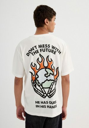 Camiseta de algodón blanca con un gran gráfico en la parte posterior que presenta llamas, un globo y texto en negrita negra y naranja. Mangas cortas.
