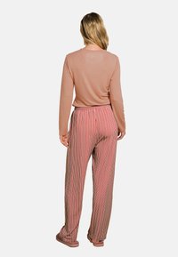 Light pink long-sleeve top paired with red and white striped wide-leg pants. Smooth texture and elastic waistband. Simple footwear.