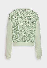 Felpa accorciata verde chiaro con motivo floreale sulla parte superiore e maniche verdi unite. Tessuto morbido e testurizzato con polsini a coste.