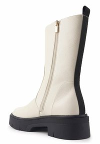 Botín tobillo de imitación de cuero blanco con punta redonda, cremallera vertical y cuerpo texturizado. Acento elástico negro en la parte trasera; suela gruesa negra.