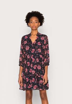 Vestido preto com padrão floral, apresentando decote em V, mangas bufantes longas e saia em camadas. O padrão floral inclui flores cor-de-rosa e azuis sobre um fundo escuro.