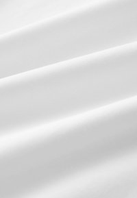 Tela blanca con una textura suave y lisa; múltiples pliegues crean suaves ondas. La superficie parece uniforme y homogénea, sin patrones visibles.