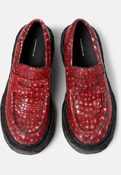 Coppia di mocassini in pelle rossa con motivo effetto coccodrillo, suole nere spesse e "CAMPERLAB" stampato all'interno della soletta nera.