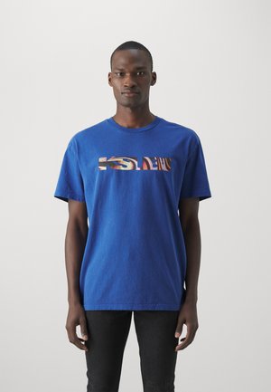 Blaues Baumwoll-T-Shirt mit einem rechteckigen Grafikdruck mit bunten Mustern auf der Brust. Kurze Ärmel und ein Rundhalsausschnitt.