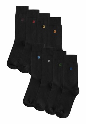 Schwarze Socken mit glatter Textur, die kleine farbige "N"-Logos in Rot, Gelb, Blau, Grau und Grün am Bündchen aufweisen. Set von acht Paaren.
