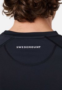 Zwarte sportshirt met een ronde halslijn, gestikte naden en het "SWEDEMOUNT" logo in het wit op de rug gedrukt.