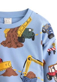 Jasnoniebieska bluza z kolorowymi kreskówkowymi pojazdami, takimi jak ciężarówki i koparki, z brązowymi wzorami ziemi i żółtymi liniami drogowymi.