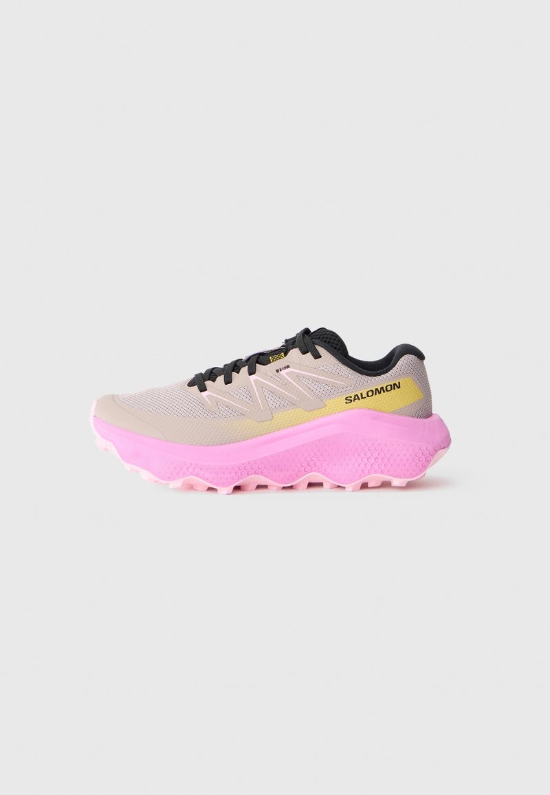 Chaussure de course Salomon beige clair et rose avec des lacets noirs et une semelle épaisse texturée, vue de profil sur un fond uni.