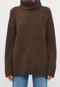 Brauner Strickpullover mit hohem Kragen, gerippten Bündchen und Saum. Strukturierter Stoff mit bunten Sprenkeln, langen Ärmeln und lockerer Passform.