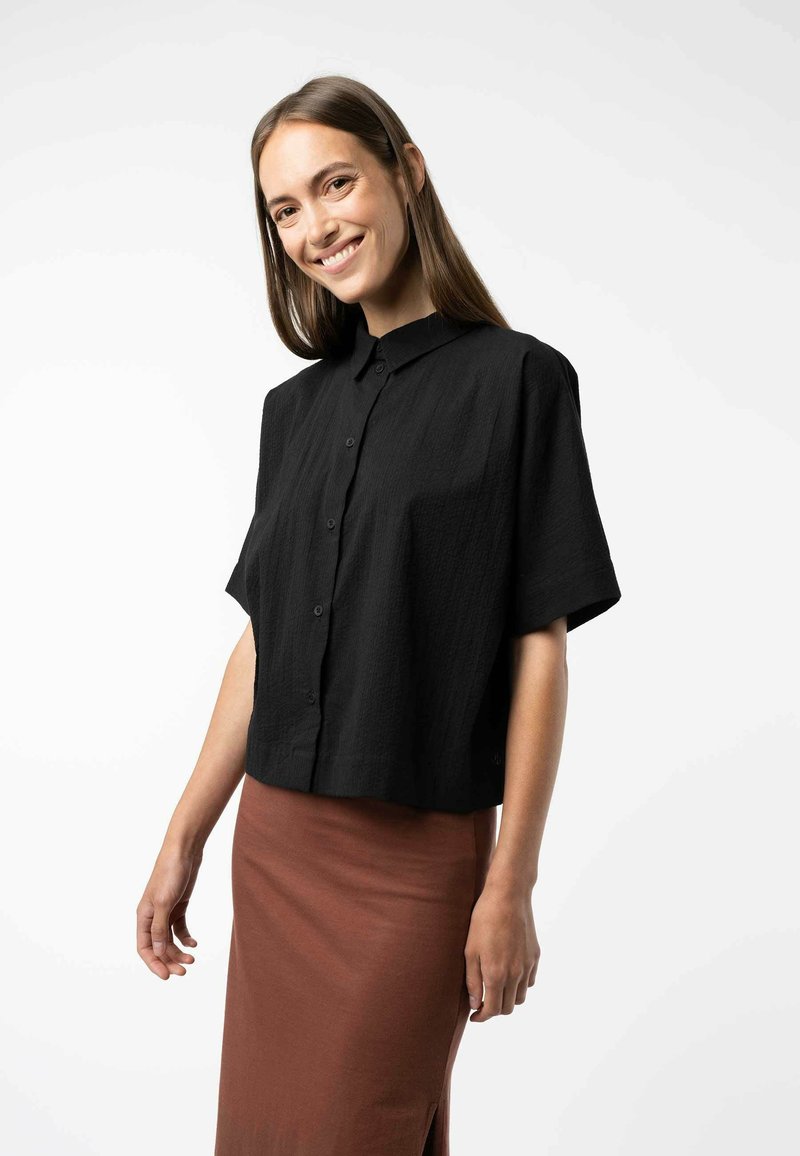 Zwarte short-sleeve knoopshirt gemaakt van gebreid stof, met een kraag en een losse pasvorm, gecombineerd met een bruine rok.