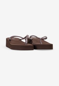 Chanclas de plataforma marrones con tiras moradas estrechas, suelas planas y una textura suave. Diseñadas para el uso casual. Base antideslizante.