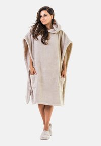 Beige fleece poncho med huva, med två framfickor. Mjuk textur, överdimensionerad design, midjelen längd, lämplig för avkoppling.