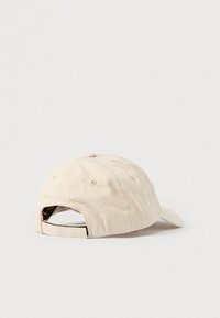 Bēšs kokvilnas beisbola cepure ar liektu sauli un regulējamu siksnu aizmugurē. Aprīkota ar izšūtām ventilācijas caurumiem un gludu tekstūru.