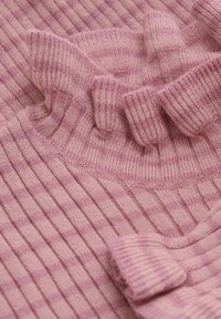 Rosa ribbad stickad tröja med volangkrage, med texturerad tyg och subtila variationer i nyanser och mönster genom hela plagget.
