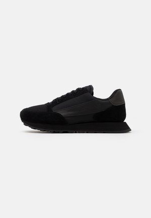 Zwarte lage sneaker met mesh- en suède details, rubberen zool, vetersluiting en subtiele branding op het zijpaneel.