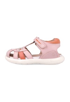 Sandalias infantiles rosas con un diseño abierto, material de cuero, costuras decorativas en forma de flor y una correa de Velcro en la parte superior. Suela blanca.