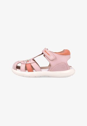 Sandalias infantiles rosas con un diseño abierto, material de cuero, costuras decorativas en forma de flor y una correa de Velcro en la parte superior. Suela blanca.