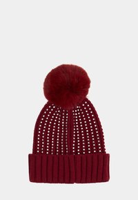 Berretto in maglia color borgogna con pompon peloso. Presenta righe verticali e file di borchie argentate sulla parte superiore e un polsino a coste.