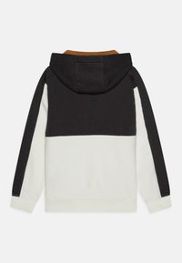 Sudadera con capucha que presenta un diseño de bloques de color en negro, blanco y un acento marrón. Material de algodón con una textura suave.