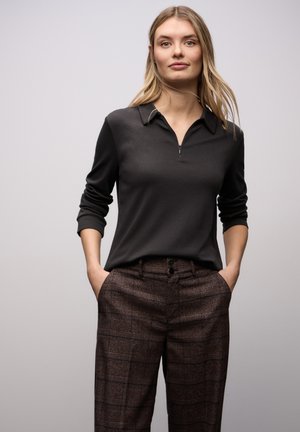 Dunkelgrauer Viertel-Reißverschluss-Pullover mit Kragen, kombiniert mit braunen, hoch taillierten karierten Hosen mit zwei Knöpfen an der Taille.