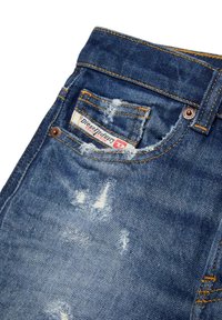 Jeans in denim lavaggio blu con effetto usurato, caratterizzati da un'etichetta sulla tasca, cuciture gialle e bordi sfrangiati per un effetto di texture.