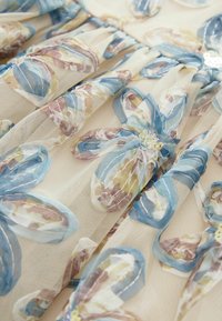 Beige sheer fabric with layered floral embroidery in blue, brown, and yellow tones, featuring embroidered petals and small bead clusters.