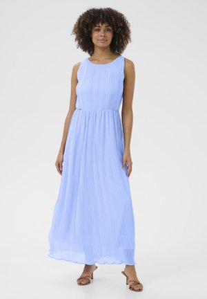 Abito lungo plissettato di colore azzurro chiaro con scollatura a giro e vita aderente. Indossato con sandali con cinturini, presenta un tessuto fluido e testurizzato.
