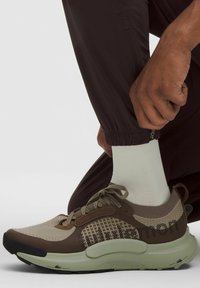 Tannfarbene und olivgrüne Sportschuhe verfügen über ein strukturiertes Obermaterial mit einem braunen Musterdesign, runder Zehenform und einer dicken, gepolsterten Sohle.