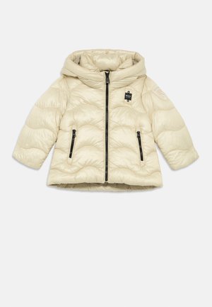 Puffermantel in hellem Beige mit Kapuze, gesteppter Textur, schwarzen Reißverschlüssen und einem Logo-Patch am Ärmel. Weiches, glänzendes Material.