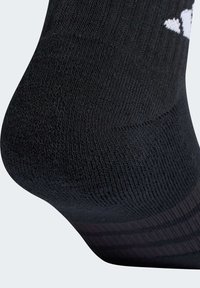 Sort sok med tekstureret vævning, buet hæl og hvidt logodetalje. Stoffet virker elastisk og tætsiddende for komfort.