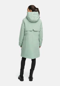 Mintgroene parka jas met een hoge kraag, elastische mouwen en een logo op de rug. Heeft een uniek achterontwerp en een knielange snit.