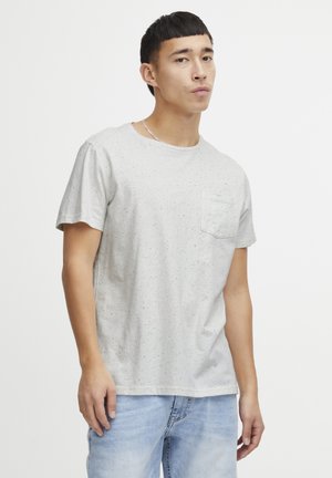 Light grey short-sleeve t-shirt in a speckled pattern, featuring a round neckline and a small chest pocket. Worn with light blue jeans.